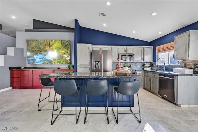 kitchen with lofted ceiling, sink, appliances with stainless steel finishes, backsplash, and a kitchen island