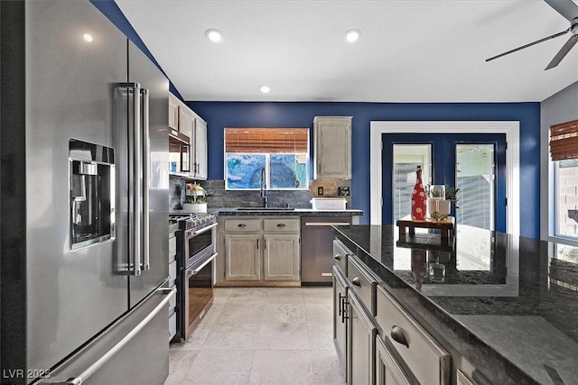 kitchen featuring light brown cabinetry, sink, stainless steel appliances, and dark stone countertops