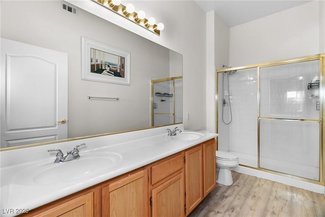 bathroom with vanity, toilet, an enclosed shower, and hardwood / wood-style floors