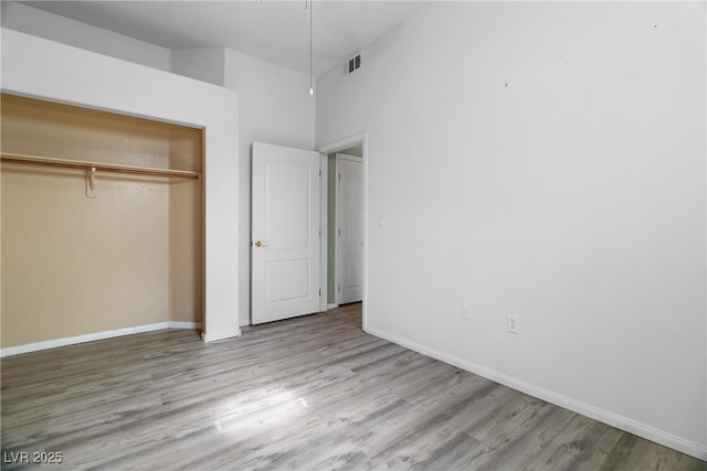 unfurnished bedroom with light wood-type flooring and a closet