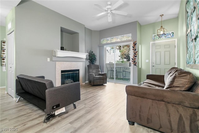 living room featuring ceiling fan, a fireplace, and light hardwood / wood-style flooring