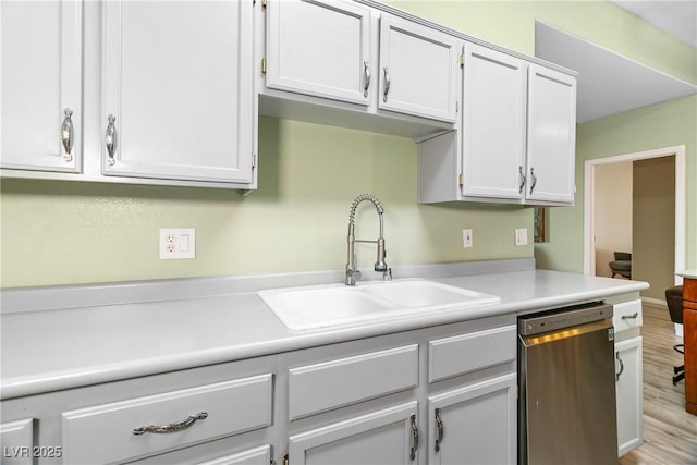 kitchen with sink, stainless steel dishwasher, white cabinets, and light hardwood / wood-style flooring