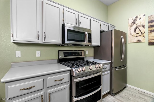 kitchen with white cabinetry, stainless steel appliances, and light hardwood / wood-style floors