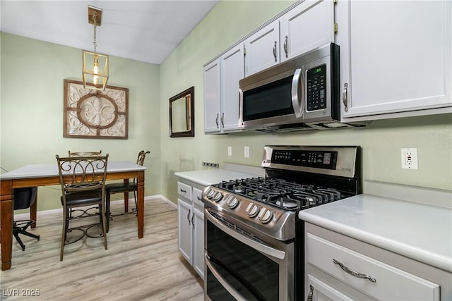 kitchen featuring white cabinetry, hanging light fixtures, light hardwood / wood-style flooring, and appliances with stainless steel finishes