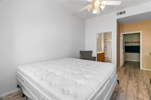 bedroom featuring ceiling fan, ensuite bathroom, a spacious closet, and light wood-type flooring