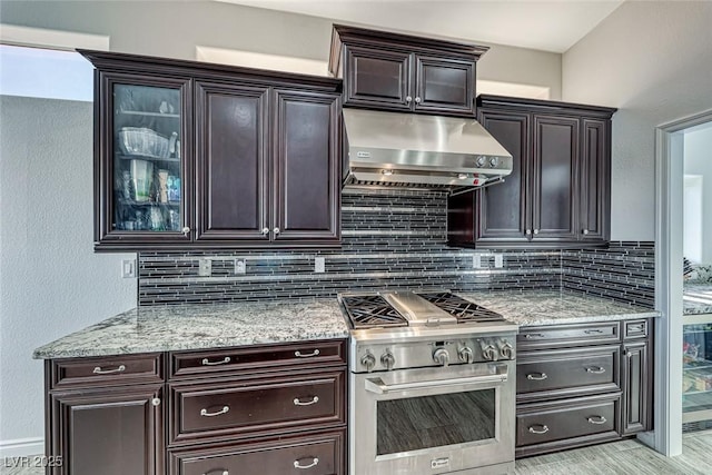 kitchen featuring high end stove, dark brown cabinets, extractor fan, and decorative backsplash