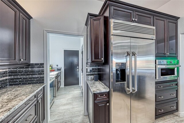 2540 Youngdale Dr, Las Vegas, NV 89134 - kitchen with dark brown cabinets, light stone countertops, appliances with stainless steel finishes, and decorative backsplash