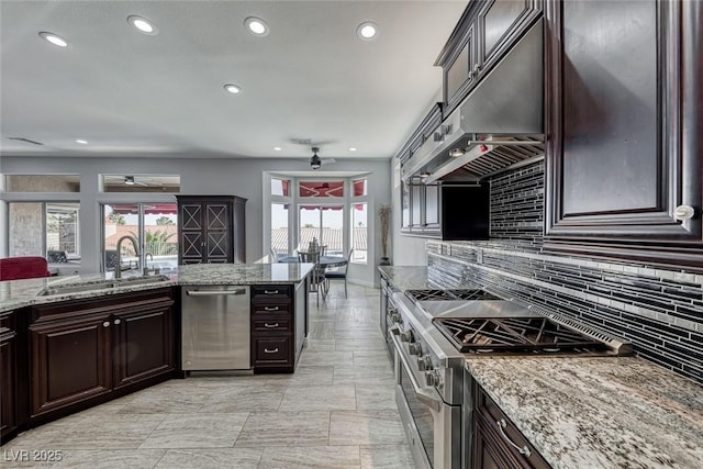 kitchen with a wealth of natural light, backsplash, appliances with stainless steel finishes, a sink, and under cabinet range hood