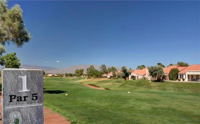 view of community with view of golf course, a mountain view, and a yard