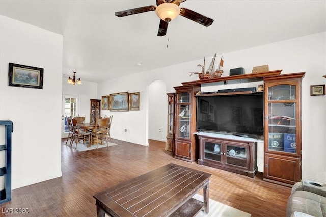 living room with ceiling fan with notable chandelier and dark hardwood / wood-style floors