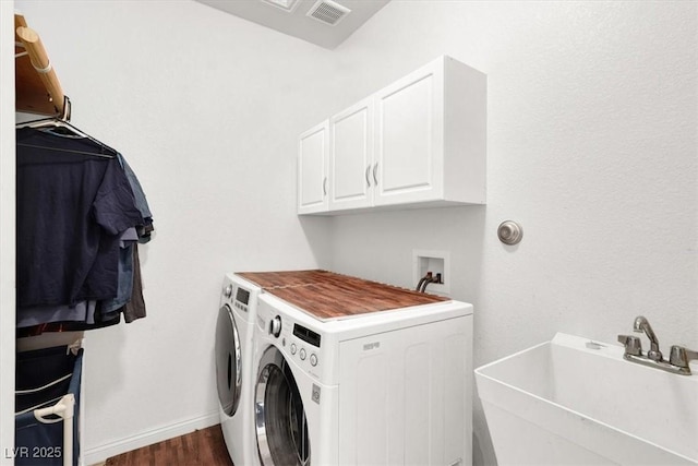 clothes washing area with sink, dark hardwood / wood-style floors, cabinets, and washing machine and clothes dryer