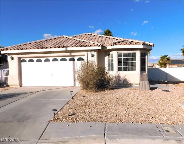 view of front of home featuring a garage, driveway, a tiled roof, and stucco siding