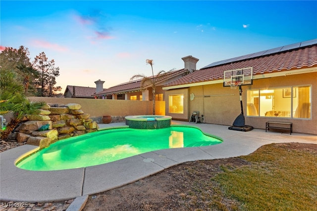 pool at dusk with a patio and an in ground hot tub