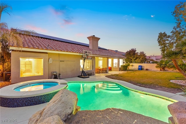 pool at dusk with a patio area, an in ground hot tub, central AC unit, and a lawn