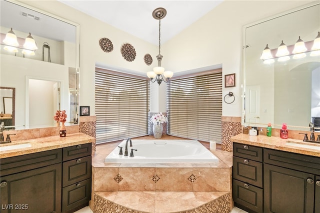 bathroom featuring tiled tub, vanity, and a notable chandelier