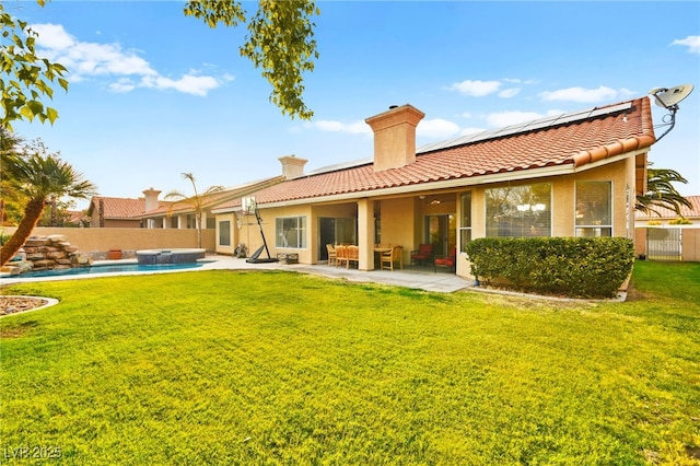 rear view of house featuring a fenced in pool, a lawn, a patio, and solar panels