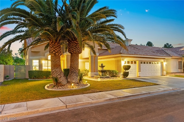 mediterranean / spanish house with a garage and a lawn