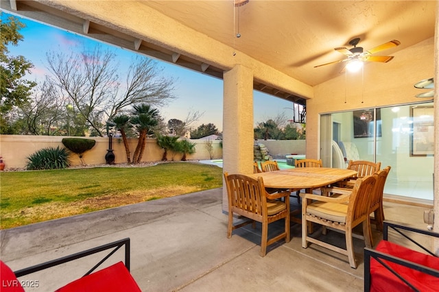 patio terrace at dusk with ceiling fan and a lawn