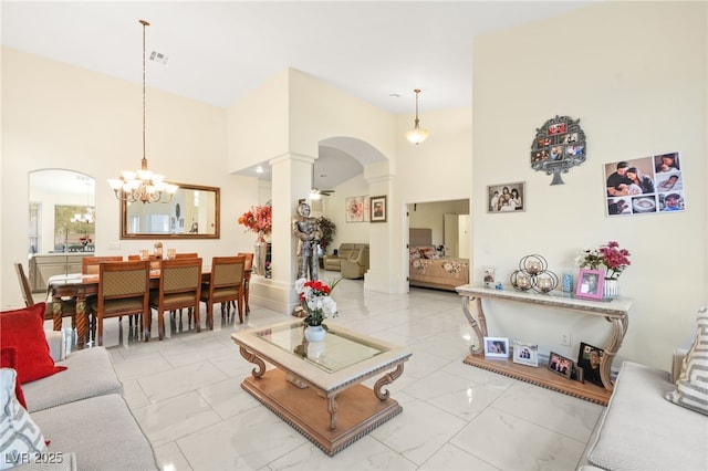 living room with a notable chandelier, a towering ceiling, and decorative columns