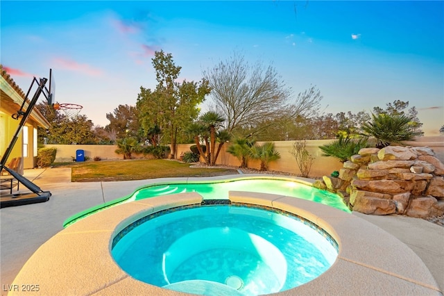 pool at dusk featuring an in ground hot tub