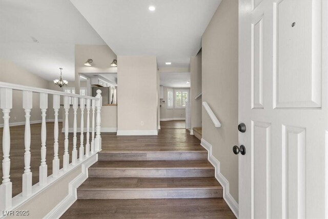 staircase featuring an inviting chandelier and hardwood / wood-style floors