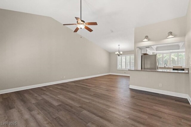 unfurnished living room featuring dark wood-type flooring, lofted ceiling, and ceiling fan with notable chandelier