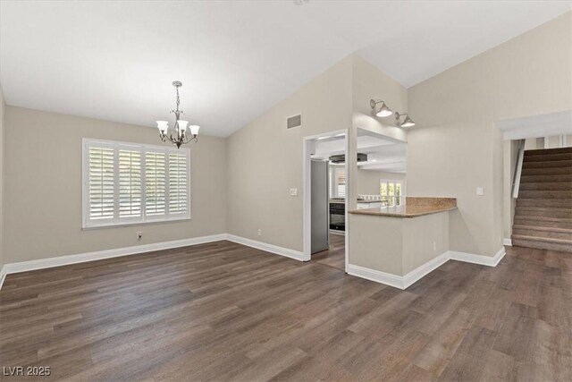 interior space with plenty of natural light, dark hardwood / wood-style floors, kitchen peninsula, and vaulted ceiling