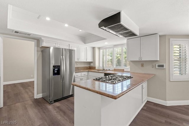 kitchen with appliances with stainless steel finishes, white cabinetry, kitchen peninsula, custom exhaust hood, and a raised ceiling