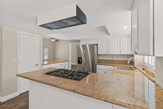 kitchen with sink, white cabinetry, stainless steel fridge, kitchen peninsula, and light stone countertops