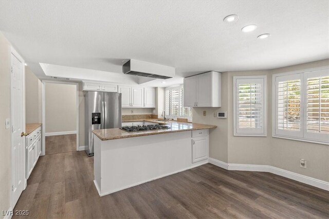 kitchen featuring white cabinetry, dark hardwood / wood-style flooring, kitchen peninsula, and appliances with stainless steel finishes