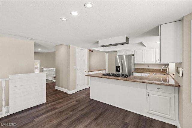 kitchen featuring stainless steel appliances, dark wood-type flooring, white cabinets, a sink, and a peninsula