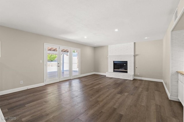 unfurnished living room featuring dark hardwood / wood-style flooring, a fireplace, and french doors