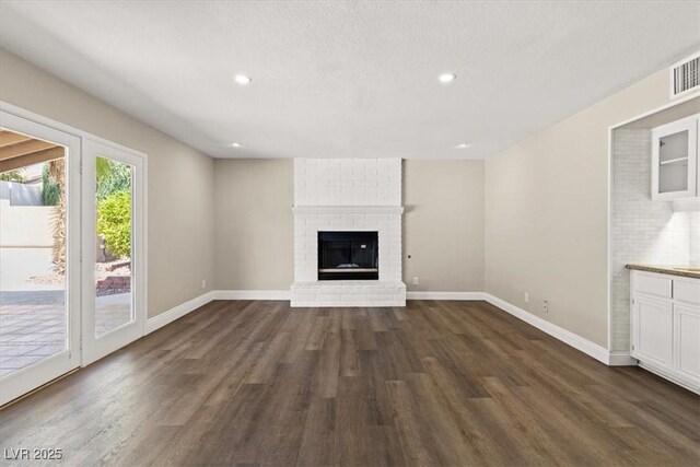 unfurnished living room featuring dark wood-type flooring, a fireplace, and a textured ceiling