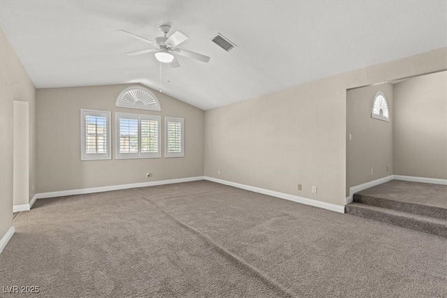 empty room featuring lofted ceiling, carpet floors, visible vents, and a healthy amount of sunlight