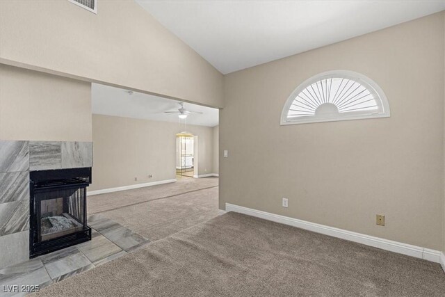 unfurnished living room with a tile fireplace, vaulted ceiling, a wealth of natural light, and light carpet