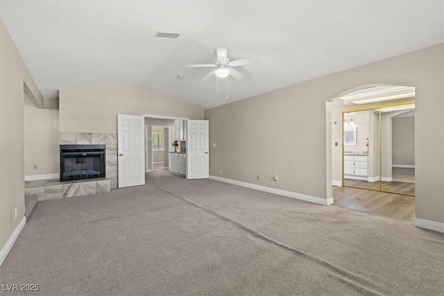 unfurnished living room with vaulted ceiling, carpet flooring, ceiling fan, and a fireplace