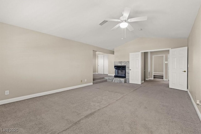 unfurnished living room featuring lofted ceiling, a tile fireplace, ceiling fan, and carpet