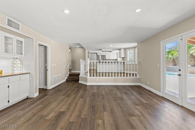 unfurnished room with dark wood-style floors, stairs, and visible vents