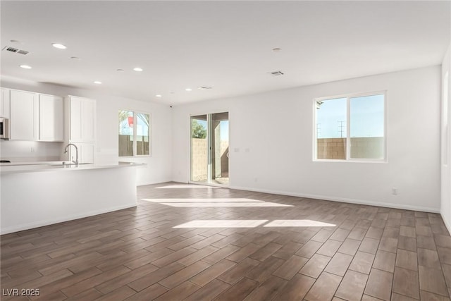 unfurnished living room with sink and dark wood-type flooring