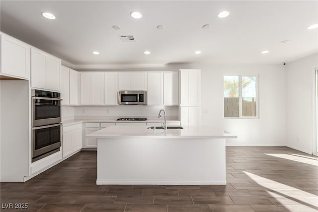 kitchen featuring appliances with stainless steel finishes, sink, a center island with sink, and white cabinets