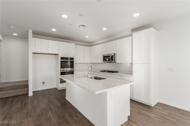 kitchen with stainless steel appliances, a kitchen island with sink, sink, and white cabinets