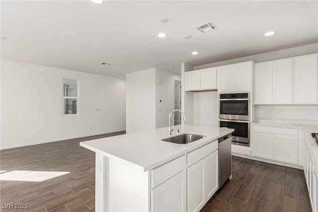 kitchen with a kitchen island with sink, sink, white cabinets, and appliances with stainless steel finishes