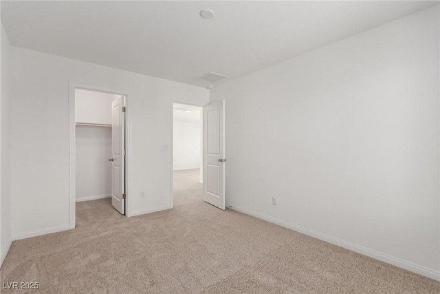 unfurnished bedroom featuring a walk in closet, light colored carpet, and a closet