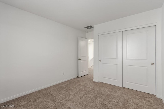 unfurnished bedroom featuring light carpet and a closet