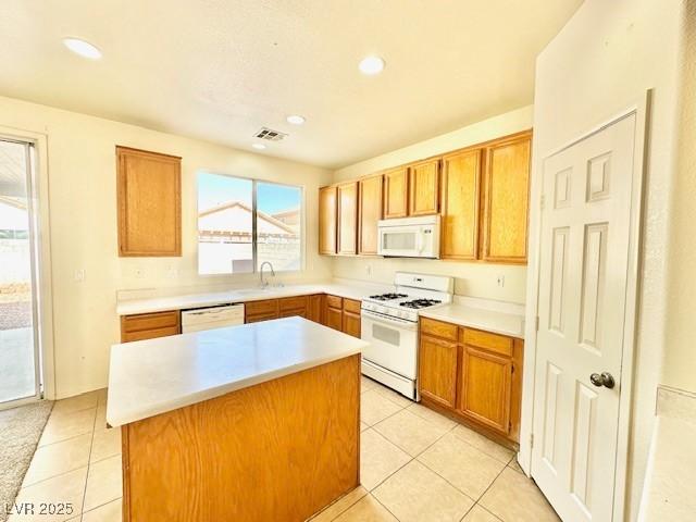 kitchen featuring white appliances, sink, a kitchen island, and light tile patterned floors