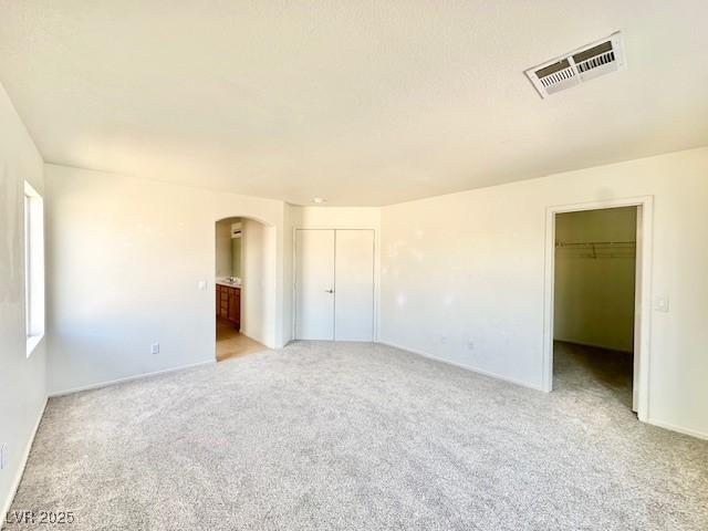 unfurnished bedroom with light colored carpet and ensuite bathroom