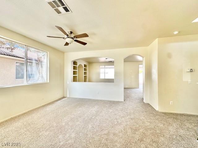 spare room with ceiling fan, light colored carpet, and a healthy amount of sunlight