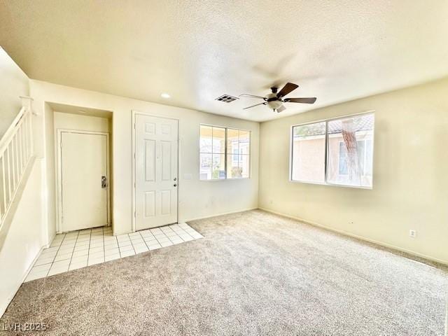 unfurnished room featuring ceiling fan, light carpet, and a textured ceiling