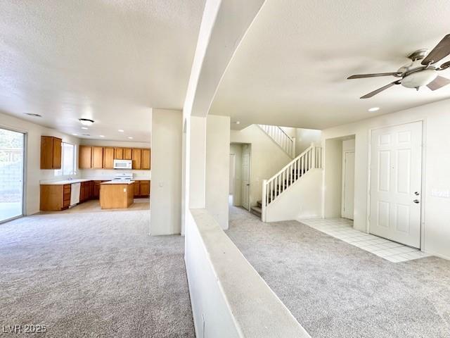 interior space with ceiling fan, light colored carpet, and a textured ceiling