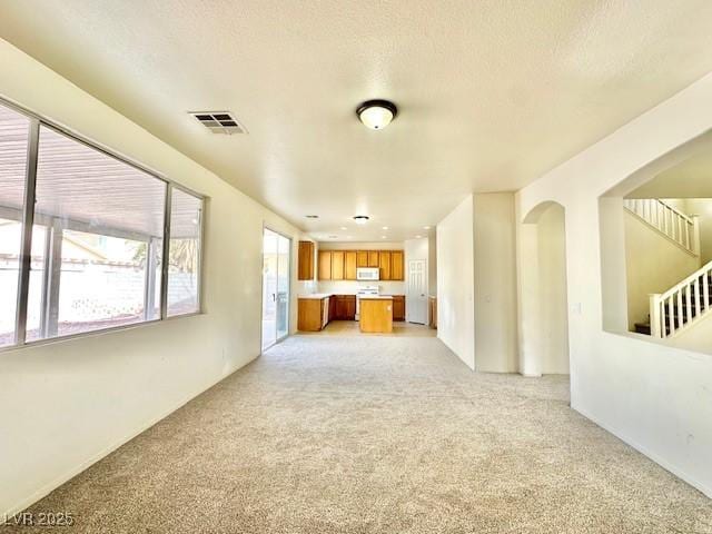 unfurnished living room with light colored carpet and a textured ceiling